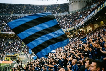 Una grande bandiera nerazzurra sventolata sugli spalti di uno stadio tra i coriandoli